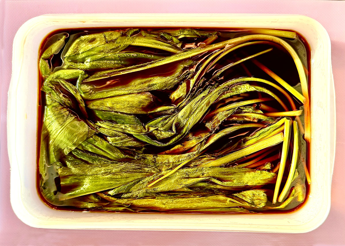 Eingelegte Bärlauchblätter in dunkler Sojasauce-Marinade in einem Glas