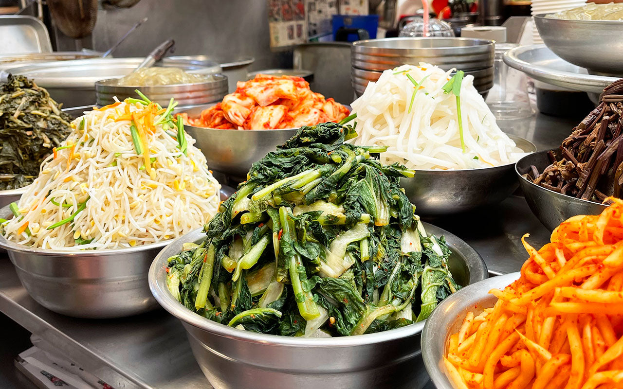 Banchan – kleine koreanische Beilagen mit Kimchi, Spinat und Bohnensprossen auf dem Tisch